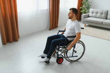 thoughtful young disabled man on wheelchair at home