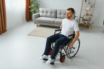 thoughtful young disabled man on wheelchair at home