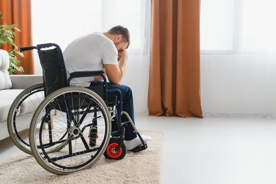 Young sad man in a wheelchair at home.