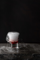 vasito de coctel con reacción química de hielo seco, fondo negro y base de piedra