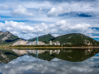 Fototapeta na wymiar Lac Des Arcs, Alberta, Canada with a beautiful relfection and a cement plant in the background