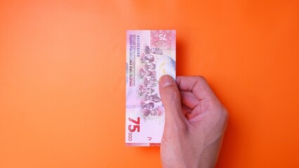 Indonesian Rupiah the official currency of Indonesia. Man's hand is making a payment. Male hand...
