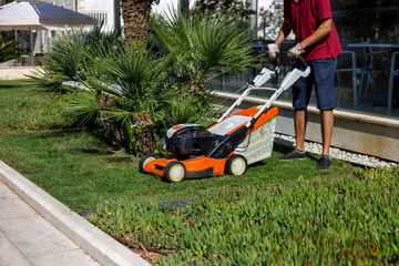Faceless man cutting the grass on the lawn with a lawn mower