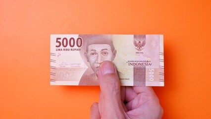 Indonesian Rupiah the official currency of Indonesia. Man's hand is making a payment. Male hand...