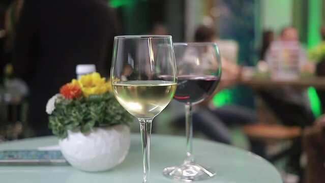 dos copas de vino en mesa con fondo de evento social borroso 