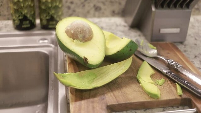 Mitades de aguacate fresco con semilla en el meson de la cocina.