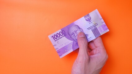 Indonesian Rupiah the official currency of Indonesia. Man's hand is making a payment. Male hand...