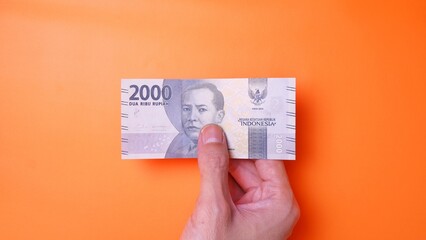 Indonesian Rupiah the official currency of Indonesia. Man's hand is making a payment. Male hand...
