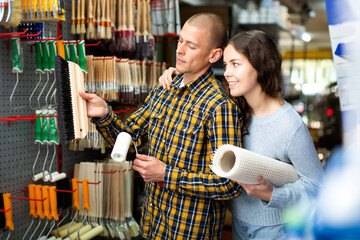 Cheerful man and woman with various goods in a building shop