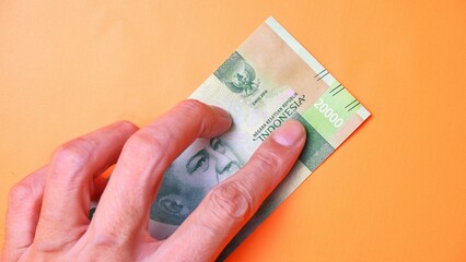 Indonesian Rupiah the official currency of Indonesia. Man's hand is making a payment. Male hand showing Indonesian Rupiah note. Business Investment Economy and Finance concept Uang 20000 20.000 Rupiah