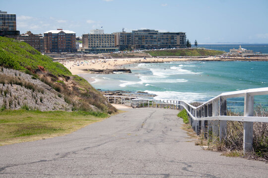 Asphalt road to a sandy beach  and a wavy ocean in Newcastle, Merewether