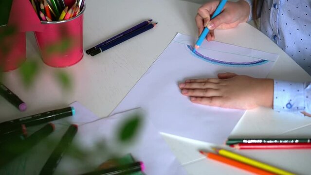 Kids creativity. Child little girl drawing rainbow with colored pencils on paper at home. Child art concept. Educational concept for school. Baby learns to draw