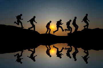 Double exposure silhouette of a man jumping on a rock reflection on water,Vivid sunset sky.