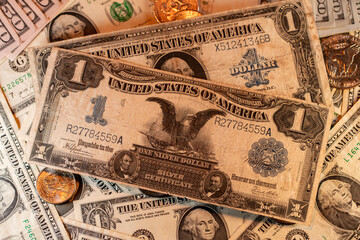 Silver certificate one Dollar banknote on top of Dollar coins and new USD banknotes issued by Federal Reserve bank