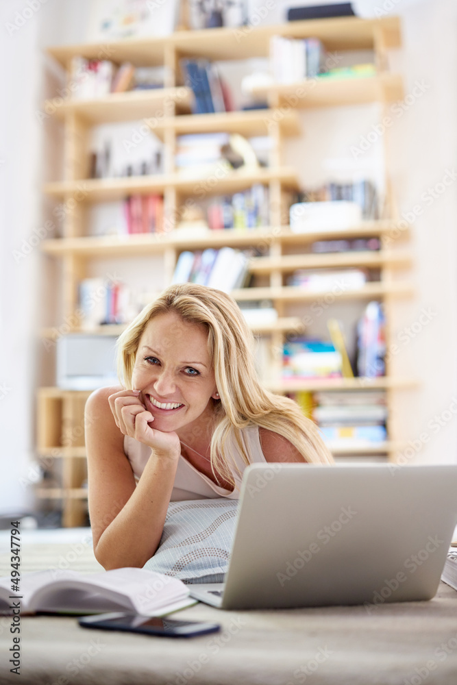 Poster staying connected is just so easy nowadays. portrait of a beautiful mature woman lying on her living