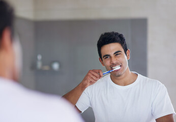He brushes twice daily for optimal oral health. Shot of a young man brushing his teeth at home.