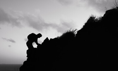 Man climbing up edge of mountain 