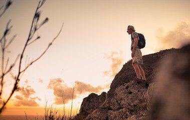 Naklejka premium Older man adventurous hiker standing on mountain cliff looking out at the view. 
