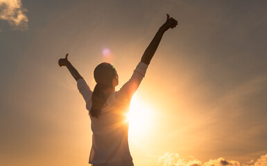 Feelings of hope, happiness  and joy. Young woman with thumbs up to the sky. 