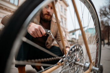 Man checking wheels on bike. Repairing bicycle at street. 