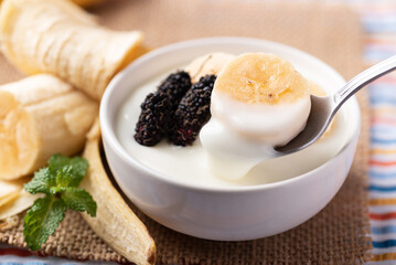 Yogurt with banana and mulberry in bowl eating by spoon, Healthy food