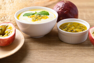 Yogurt with passion fruit juice in bowl on wooden background, Healthy eating