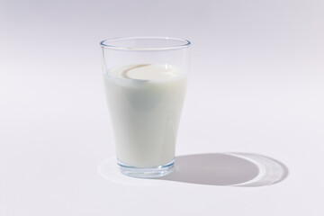 Full glass glass of milk in hard light on WHITE background. Dairy, shortage, calcium, grow and drink concept