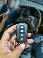 Hand hold new car alarm remote with blurry background.