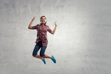Fototapeta na wymiar Woman wearing headphones jumping . Mixed media