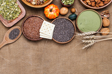 selection of healthy and clean food: seeds, superfoods, nuts, beans, biscuits on burlap background.