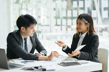 Businesspeople smiling coworking commenting and showing growth graphic and taking a business conversation in an office interior