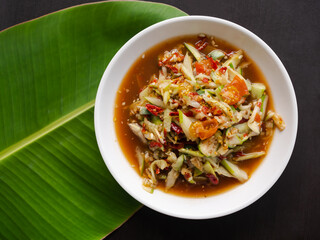 Papaya salad with cucumber. spicy food traditional of asian Thai. ingredient bitter, tomato, lemon or lime, fresh shrimp, pickled fish,vegetable and spices. food for diet good health diet concept.