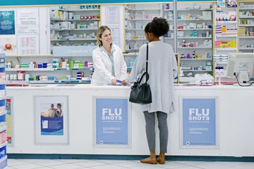 Papier Peint photo Lavable Pharmacie Let us help you fight the winter blues. Rearview shot of a young woman purchasing over the counter medication from a female pharmacist.