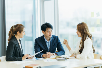 group of four happy young asian corporate people teammates meeting discussing business in office.