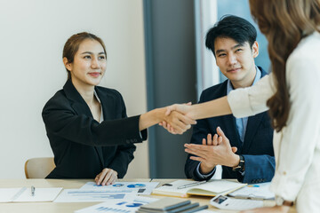two asian business partners successful handshake together in front of group teamwork casual business clapping hands winning success agreement in modern office.Partnership approval and teamwork