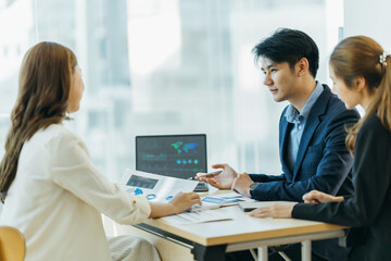 Fototapeta premium Group of asian young modern people in smart casual wear having a brainstorm meeting while sitting in office background. Business meeting, Planning, Strategy, New business development, Startup concept.