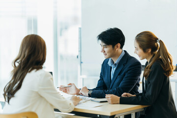 Group of asian young modern people in smart casual wear having a brainstorm meeting while sitting in office background. Business meeting, Planning, Strategy, New business development, Startup concept.