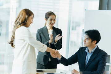 two asian business partners successful handshake together in front of group teamwork casual business clapping hands winning success agreement in modern office.Partnership approval and teamwork
