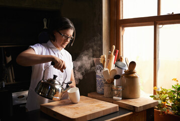 The best thing after a long day. Shot of an attractive young woman making a cup of tea in her kitchen.