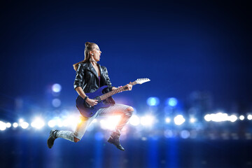 Fototapeta na wymiar Young and beautiful rock girl playing the electric guitar . Mixed media