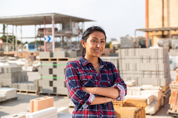 Obraz premium Portrait of positive hispanic female supervisor standing in warehouse of hardware store