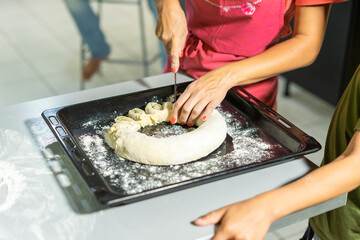 close-up. woman cuts the dough with a knife. roll lies on a baking sheet
