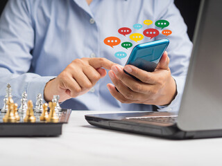 Close-up of hands using mobile phone with colorful chat icons on the application