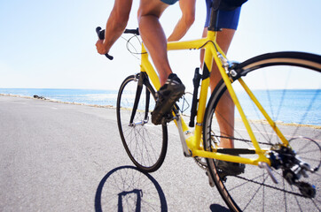 Fototapeta na wymiar Enjoying the scenery while exercising. Cropped view of a cyclist cycling along an ocean road.