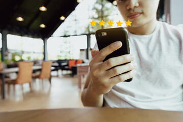 man using smartphone for giving five stars feedback,rating excellent rank to products or online shopping, indoor cafe
