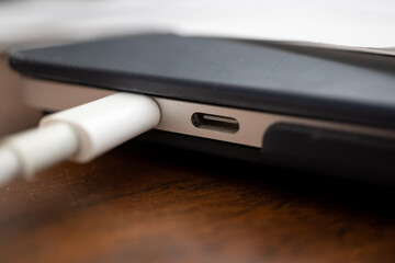 detalle de puerto usb C de laptop MacBook Pro libre junto a otro ocupado sobre mesa de madera
