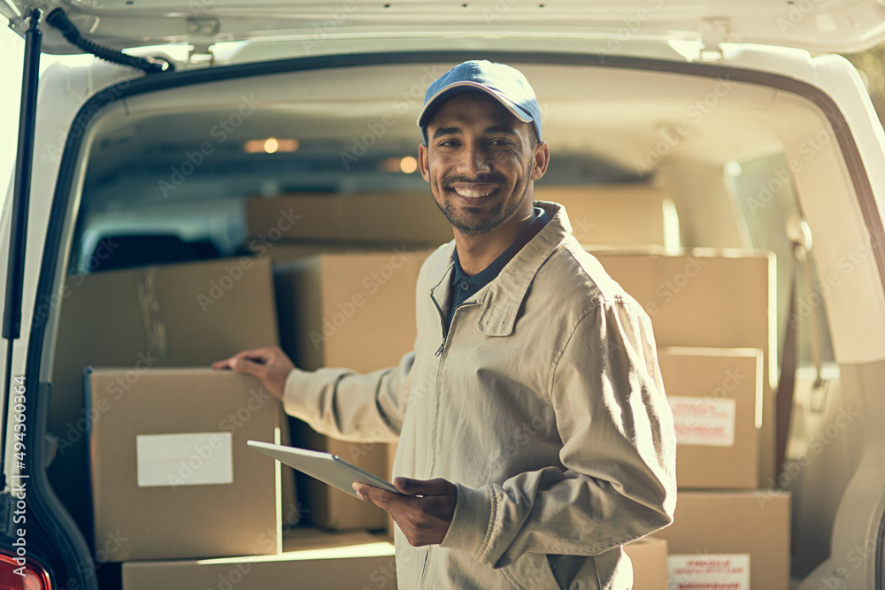Aufkleber Maintaining fast and efficient delivery. Portrait of a delivery man using a digital tablet while checking the boxes in his van.