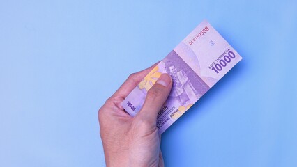 Indonesian Rupiah the official currency of Indonesia. Man's hand is making a payment. Male hand...