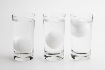 Eggs in water test on transparent glass , Egg freshness test on white background , Bad egg floats...
