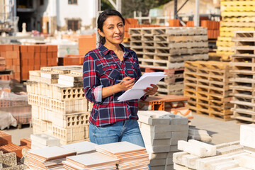 Latin American female supervisor with tablet checking quality of tiles at hardware store warehouse